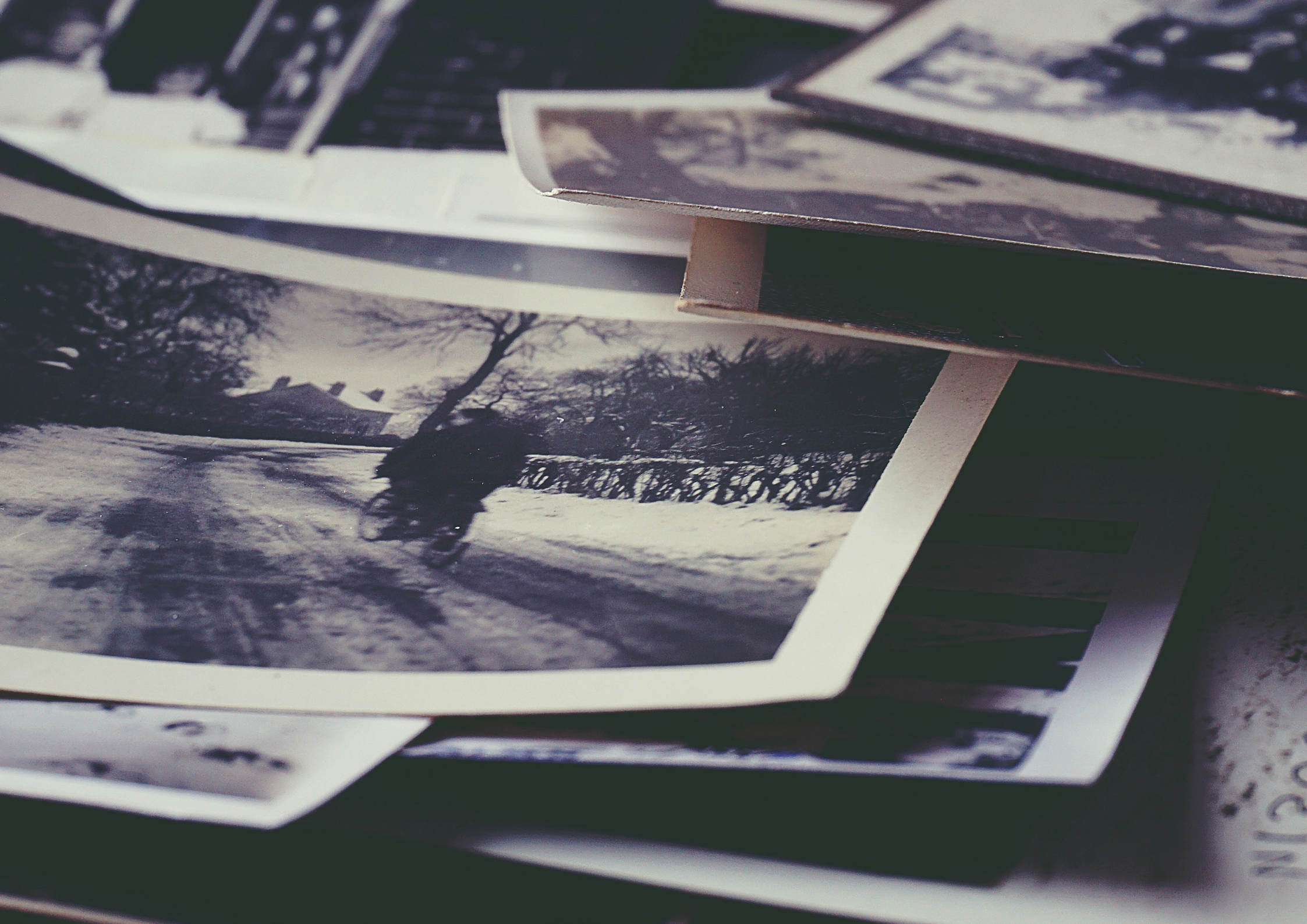 Czarno-białe fotografie leżą rozrzucone na blacie