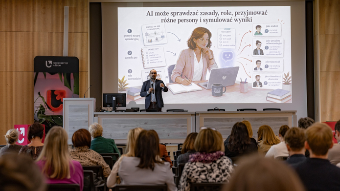 Widok na salę wykładową Uniwersytetu Łódzkiego. Na pierwszym planie uczestnicy siedzą zwróceni w stronę prowadzącego, który przemawia do mikrofonu. Za nim wyświetlana jest prezentacja dotycząca wykorzystania sztucznej inteligencji do analizowania zasad, przyjmowania różnych ról i symulowania wyników. Po lewej stronie znajduje się baner z logotypem Uniwersytetu Łódzkiego.