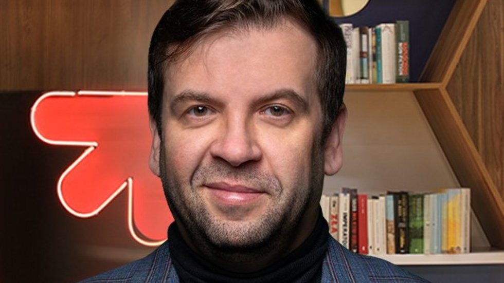 Prof. Chomczyński na tle regałów bibliotecznych i neonu z logotypem UŁ