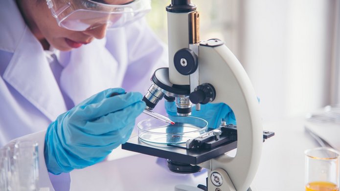 Woman scientist in lab look at science microscope medical test a Naukowczyni przeprowadzająca badania